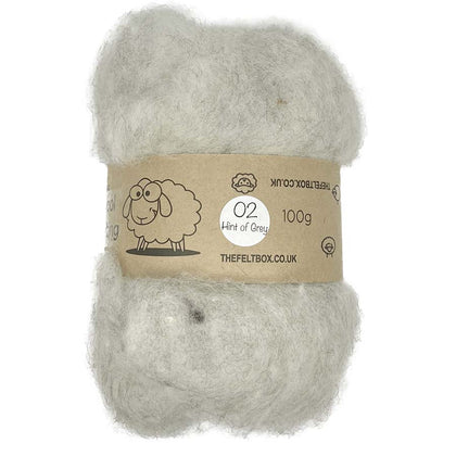 A carded wool batt in a hint of grey color, packaged in a brown paper wrapping with a label that includes the brand name 'The Felt Box' and an illustration of a sheep.