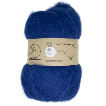 A carded wool batt in indigo color, packaged in a felt box with a label showing the product details.