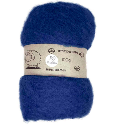 A royal blue carded wool batt for needle felting, displayed on a card with a label showing the brand and product details.