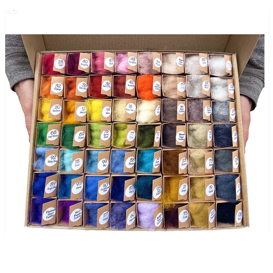 A person holding multicoloured palette of carded needle feting wool in a cardboard bow. each colour is individually labelled
