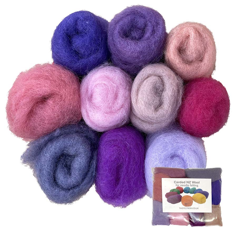 A collection of carded felting wool in pink an dpurple shades displayed as small rolls or tufts, with a label indicating the product is from The Felt Box.