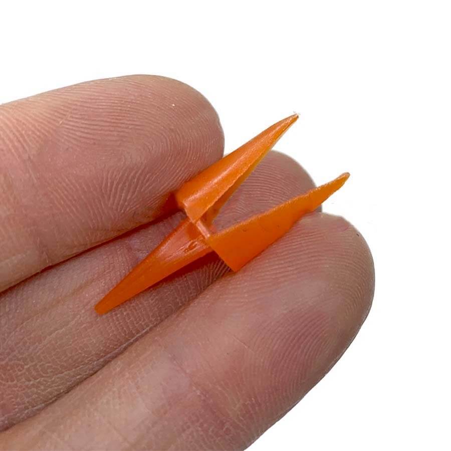 Orange plastic birds beak held between fingers on a white background