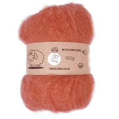 A bundle of carded wool batting in paprika color, displayed with a label indicating it is 100% sheep wool from The Felt Box, weighing 100g.