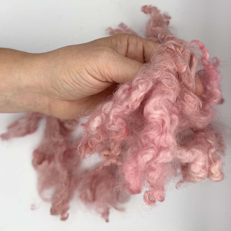 Pink Leicester Longwool locks held in hand to show curls and texture
