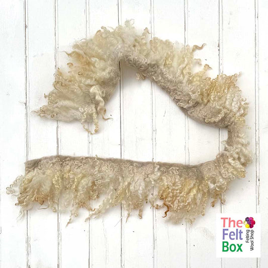 Curly cream scarf on a white wooden background with 'The Felt Box' branding.