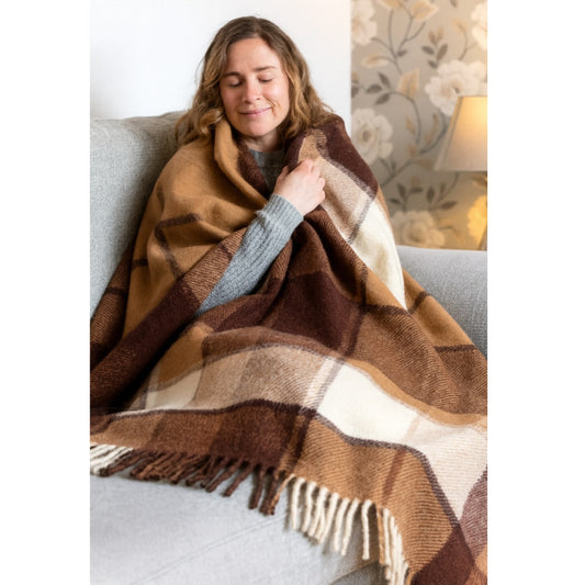Woman wrapped in a brown checkered blanket on a couch